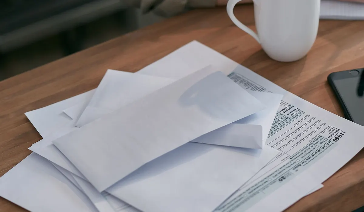 Briefumschläge und Formulare neben einer Tasse auf einem Tisch